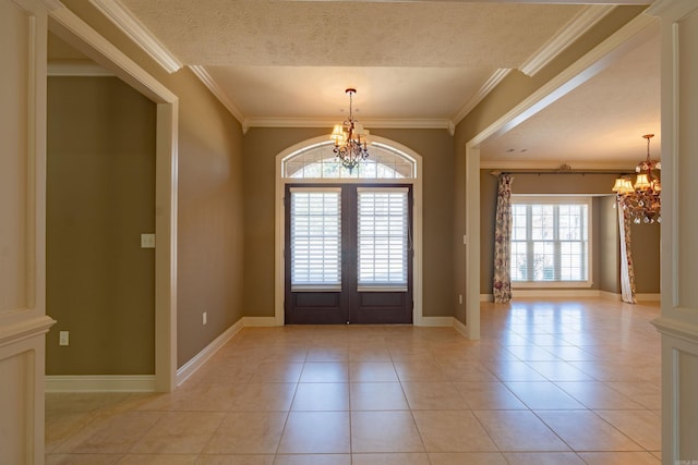 entrance foyer featuring a textured ceiling, light tile patterned flooring, ornamental molding, french doors, and an inviting chandelier