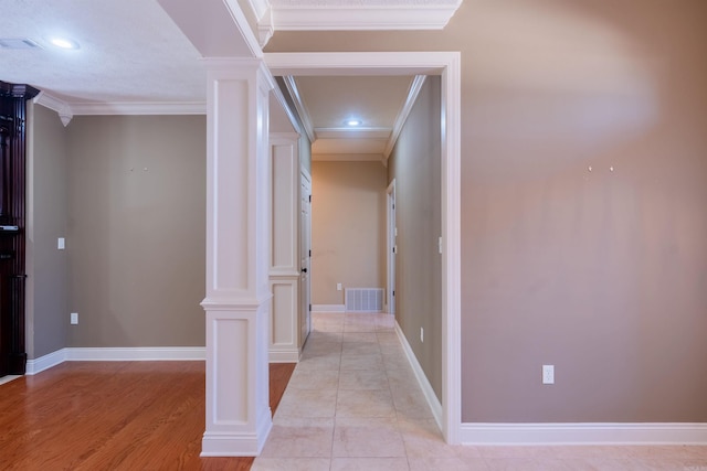 hallway with baseboards, decorative columns, visible vents, and crown molding