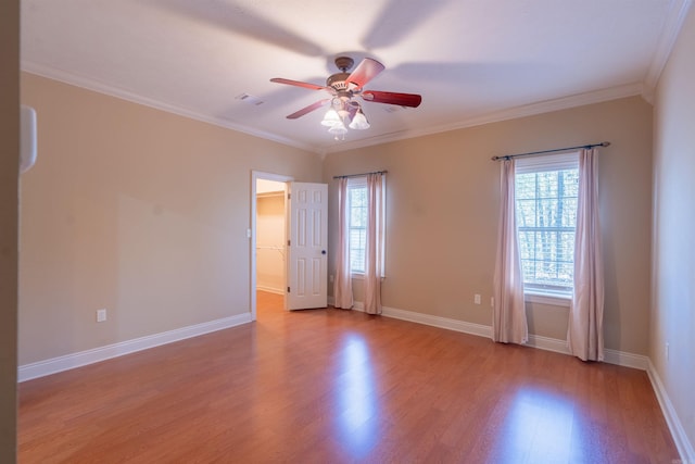 unfurnished room featuring a wealth of natural light, crown molding, baseboards, and wood finished floors
