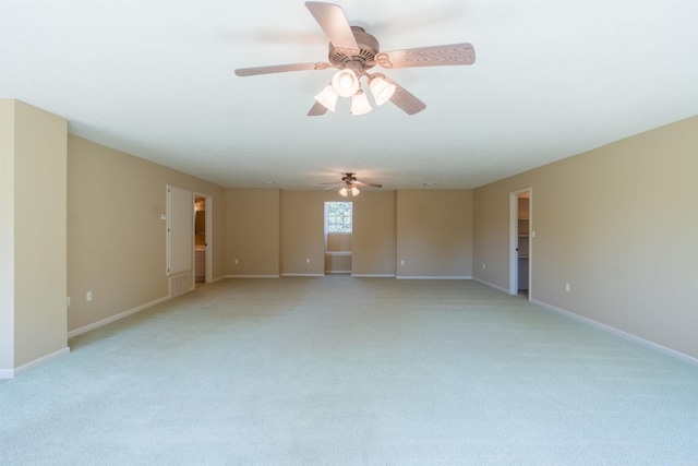 spare room with light carpet, ceiling fan, and baseboards