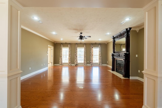 unfurnished living room with a fireplace with flush hearth, crown molding, a textured ceiling, and wood finished floors