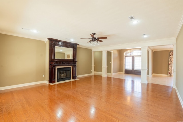 unfurnished living room with a large fireplace, visible vents, light wood-style floors, ornamental molding, and ornate columns