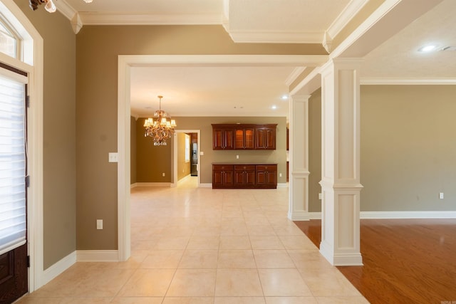 foyer entrance featuring light tile patterned floors, baseboards, crown molding, ornate columns, and a chandelier