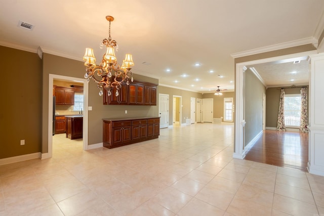 interior space with ceiling fan with notable chandelier, ornamental molding, visible vents, and baseboards