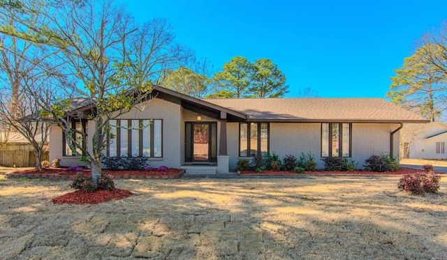 view of front of home with a shingled roof, brick siding, and a front lawn