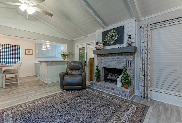 living area featuring vaulted ceiling with beams, ceiling fan, a fireplace, baseboards, and light wood-type flooring