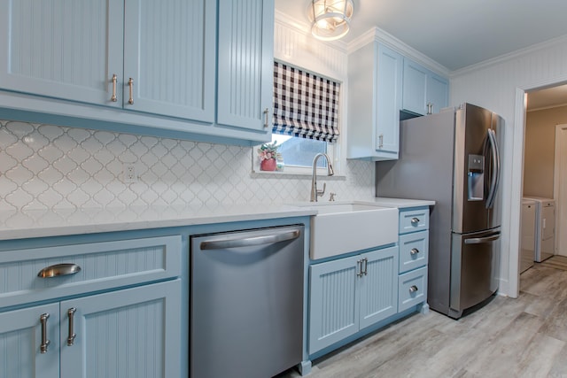 kitchen featuring washing machine and clothes dryer, light countertops, stainless steel appliances, crown molding, and blue cabinetry