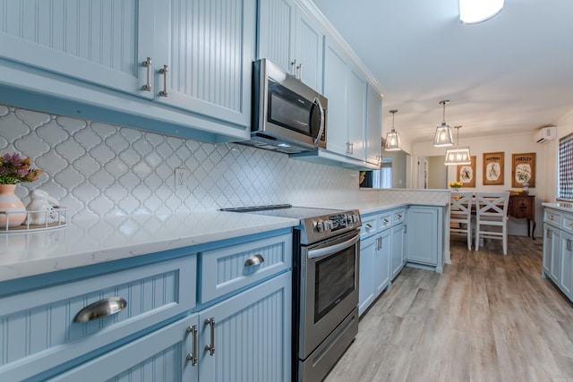 kitchen with blue cabinetry, tasteful backsplash, light countertops, hanging light fixtures, and appliances with stainless steel finishes