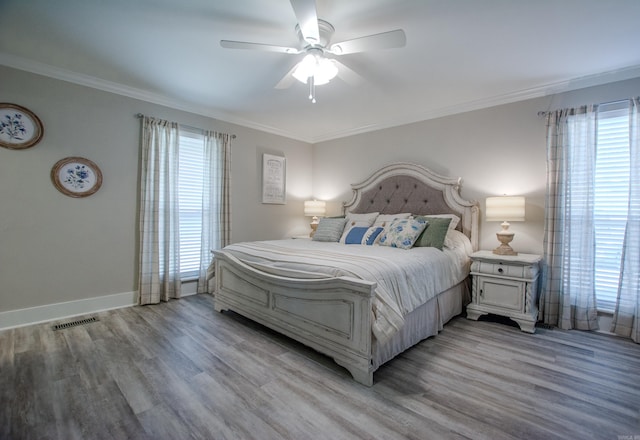 bedroom with baseboards, light wood-style flooring, visible vents, and crown molding