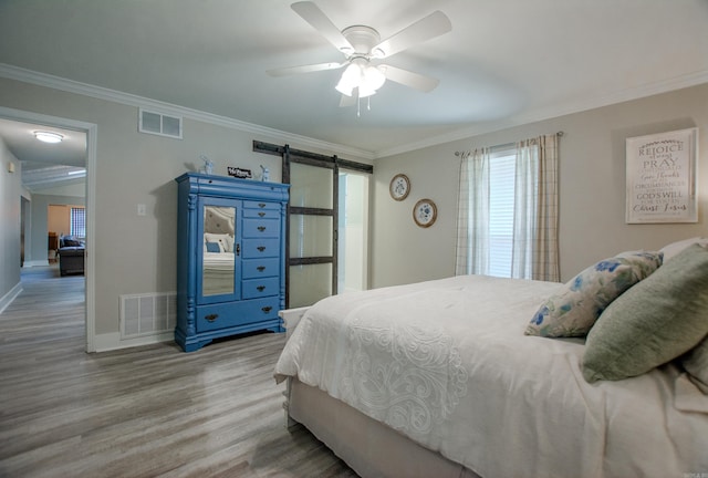 bedroom featuring a barn door, visible vents, and ornamental molding