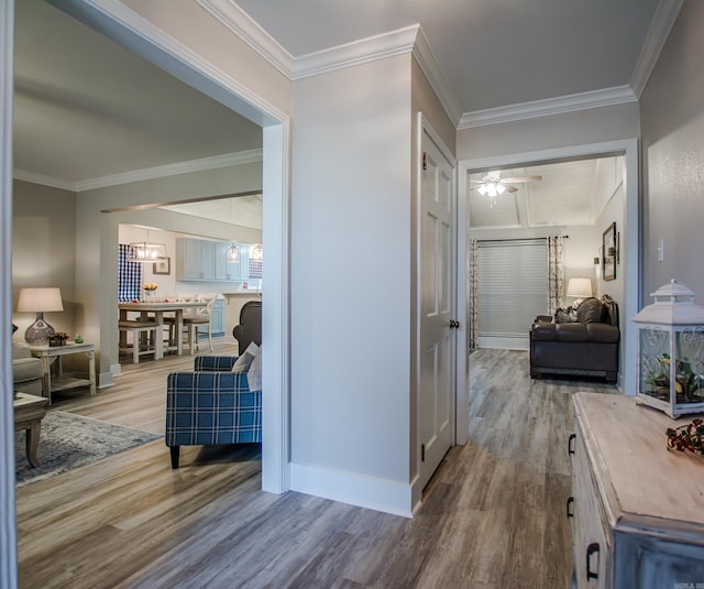 hallway featuring a notable chandelier, baseboards, ornamental molding, and wood finished floors