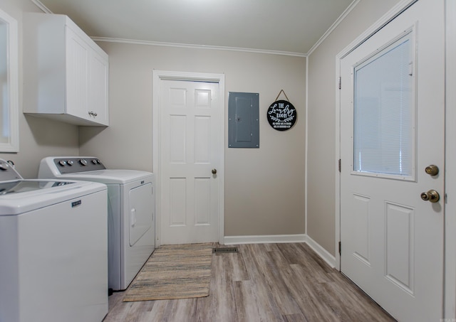 clothes washing area with cabinet space, electric panel, washing machine and clothes dryer, crown molding, and light wood-type flooring