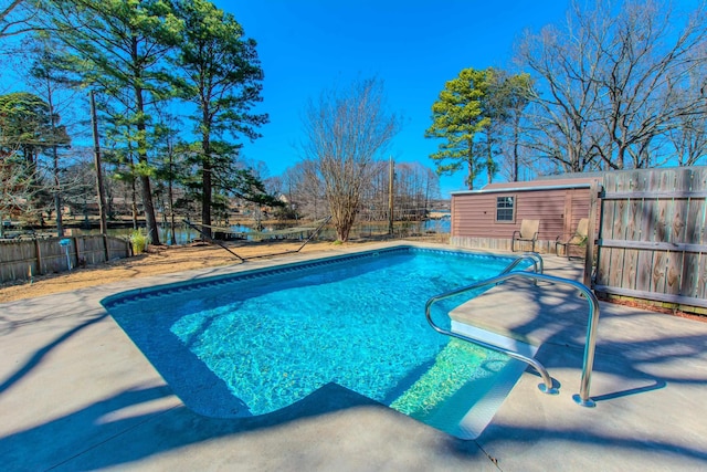 view of swimming pool featuring fence, a fenced in pool, and an outbuilding