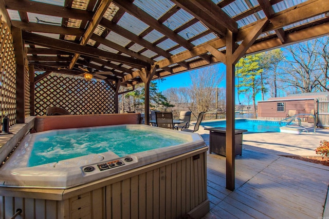 view of patio / terrace featuring an outdoor structure, a fenced in pool, and a hot tub