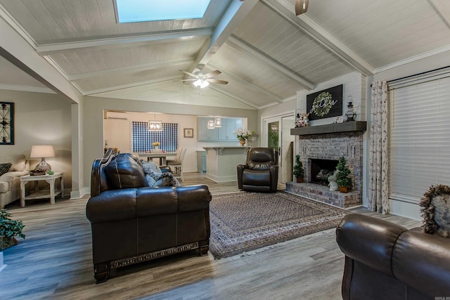 living area with a brick fireplace, vaulted ceiling with beams, baseboards, and wood finished floors