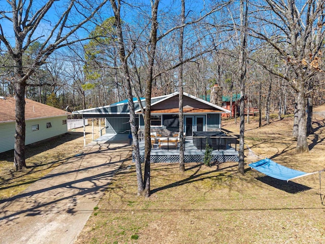 view of front of home with driveway, a chimney, a front yard, and a wooden deck