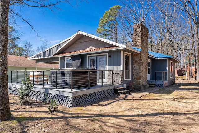 rear view of property featuring board and batten siding, metal roof, and a deck