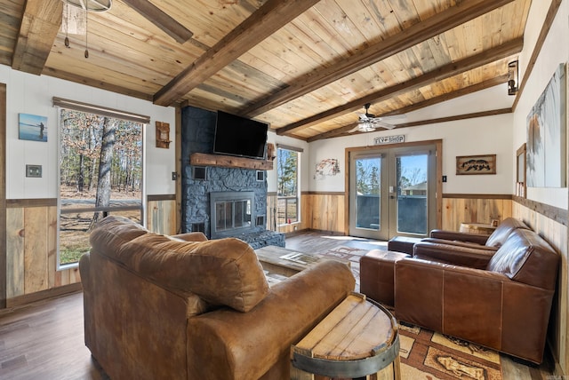 living room featuring a wainscoted wall, ceiling fan, beamed ceiling, and wooden ceiling