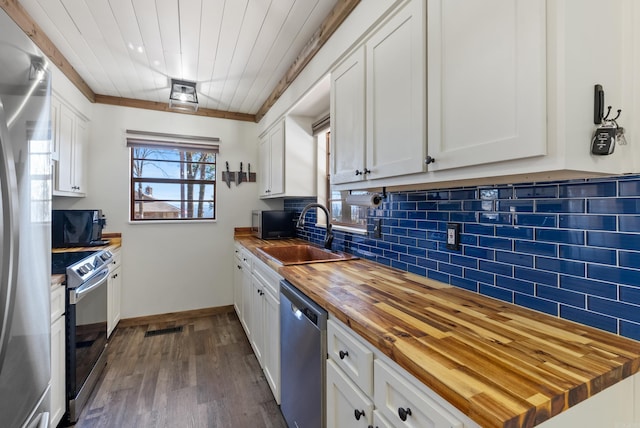 kitchen featuring tasteful backsplash, appliances with stainless steel finishes, white cabinetry, a sink, and wood counters