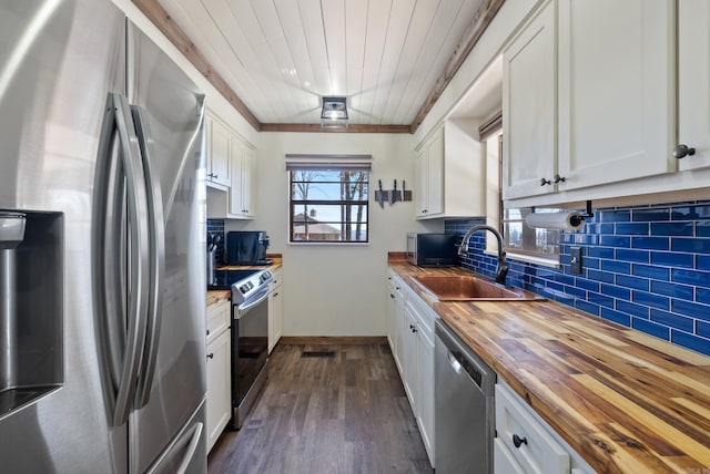 kitchen with tasteful backsplash, butcher block countertops, appliances with stainless steel finishes, white cabinetry, and a sink