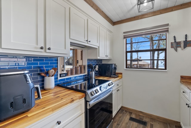 kitchen with butcher block countertops, visible vents, backsplash, white cabinets, and stainless steel range with electric stovetop