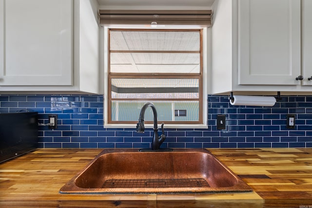 kitchen with dark countertops, white cabinetry, a sink, and wood finished floors