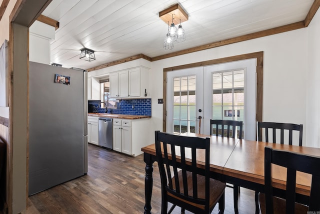 dining area featuring a healthy amount of sunlight, dark wood-style floors, an inviting chandelier, and french doors