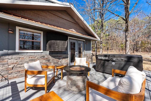 deck featuring an outdoor fire pit and a hot tub