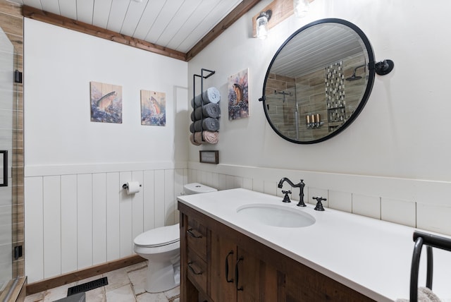 bathroom featuring visible vents, wainscoting, toilet, vanity, and a shower stall