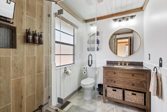 bathroom with toilet, a shower stall, vanity, and wainscoting