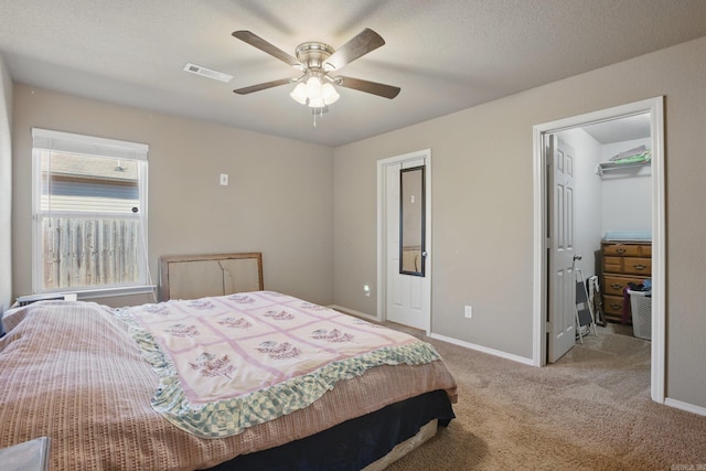 bedroom with carpet floors, visible vents, a spacious closet, ceiling fan, and baseboards