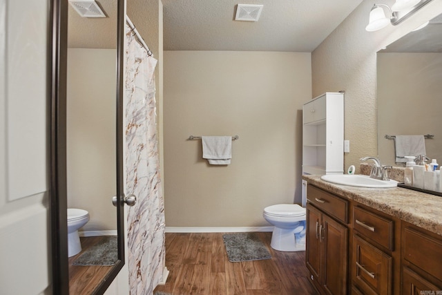 full bathroom with toilet, visible vents, wood finished floors, and vanity