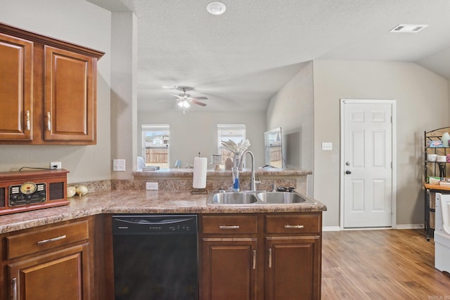 kitchen featuring visible vents, light wood-style flooring, a sink, dishwasher, and a peninsula