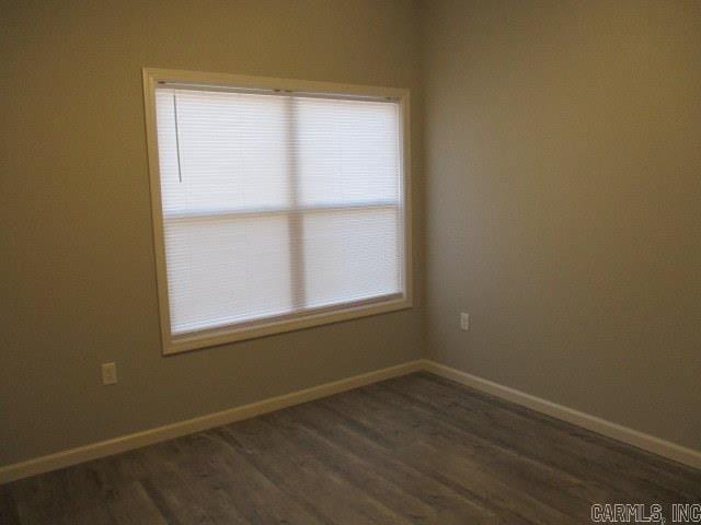 spare room with dark wood finished floors and baseboards