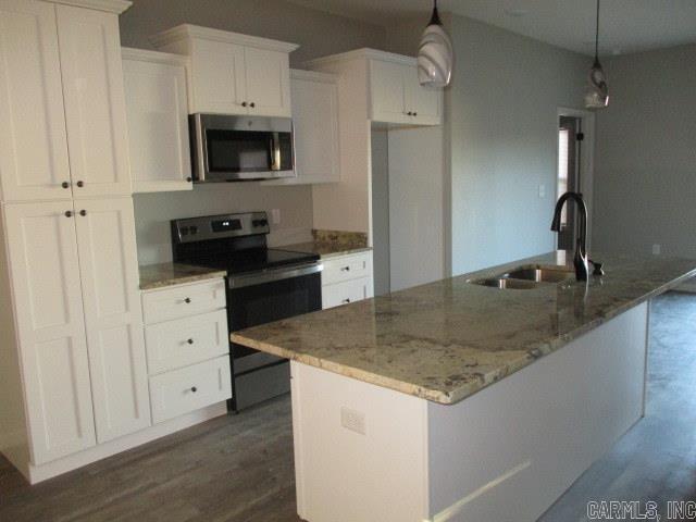 kitchen featuring appliances with stainless steel finishes, an island with sink, a sink, and white cabinetry