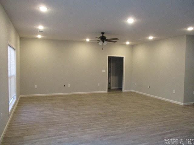 empty room featuring a ceiling fan, recessed lighting, baseboards, and wood finished floors