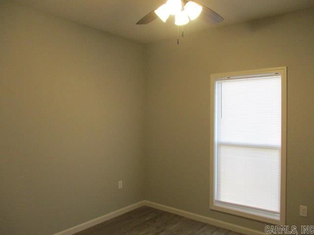 spare room featuring ceiling fan, dark wood-style flooring, and baseboards