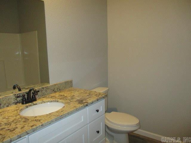 bathroom featuring toilet, baseboards, and vanity