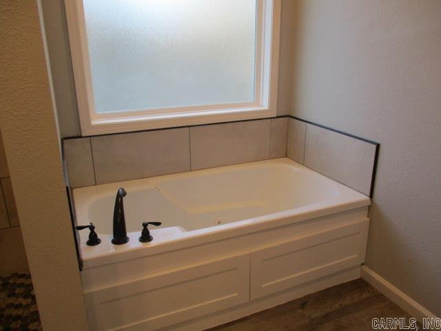 bathroom featuring a garden tub and baseboards