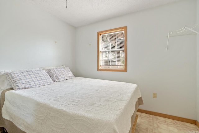 bedroom with a textured ceiling, baseboards, and tile patterned floors