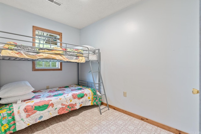 bedroom with visible vents, a textured ceiling, and baseboards