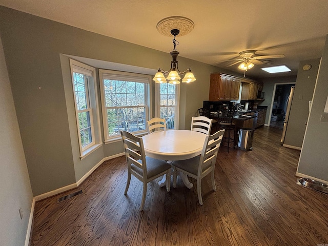 dining space featuring a notable chandelier, dark wood-type flooring, visible vents, and baseboards