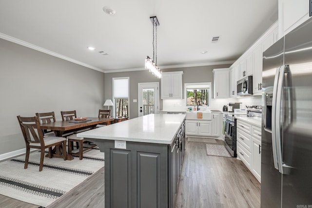 kitchen with stainless steel appliances, light wood finished floors, white cabinetry, and a center island