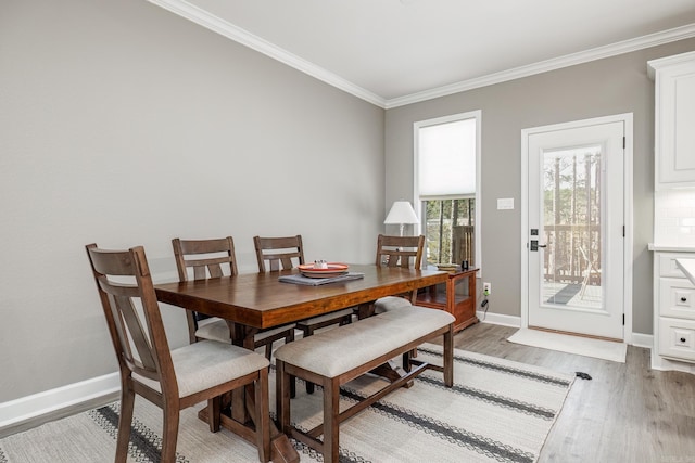 dining space with light wood-style floors, crown molding, and baseboards