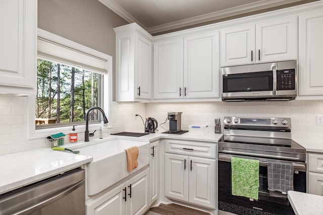 kitchen with tasteful backsplash, appliances with stainless steel finishes, white cabinets, and a sink