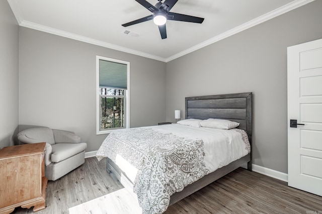 bedroom featuring crown molding, visible vents, baseboards, and wood finished floors