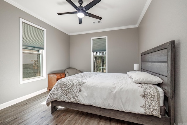 bedroom featuring crown molding, visible vents, ceiling fan, wood finished floors, and baseboards