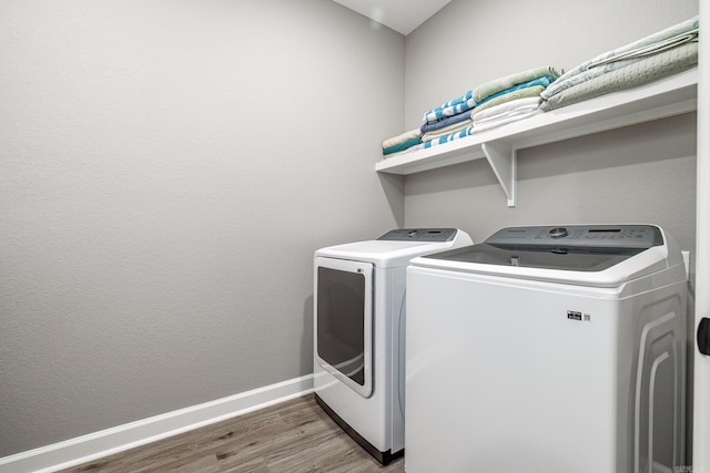laundry room featuring laundry area, separate washer and dryer, wood finished floors, and baseboards