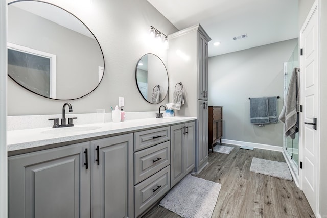 bathroom with wood finished floors, visible vents, a sink, and double vanity