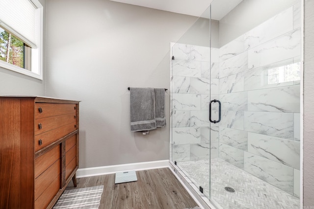 full bath with a shower stall, baseboards, and wood finished floors